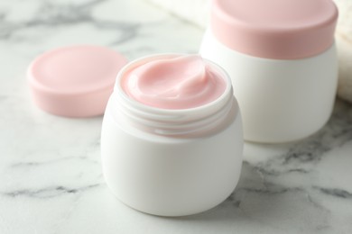Photo of Jar of moisturizing body cream on white marble table, closeup