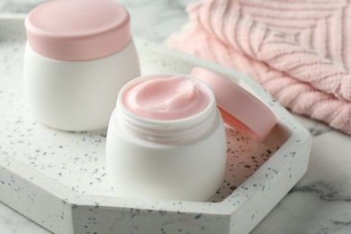 Photo of Jar of moisturizing body cream on white marble table, closeup