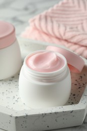 Photo of Jar of moisturizing body cream on white marble table, closeup