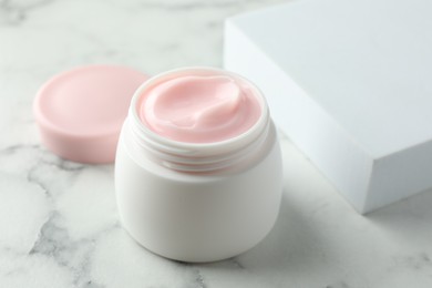 Photo of Jar of moisturizing body cream on white marble table, closeup