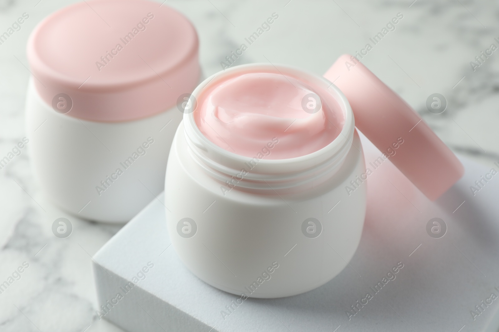 Jars of moisturizing body cream on white marble table, closeup Photo of Jars of moisturizing body cream on white marble table, closeup