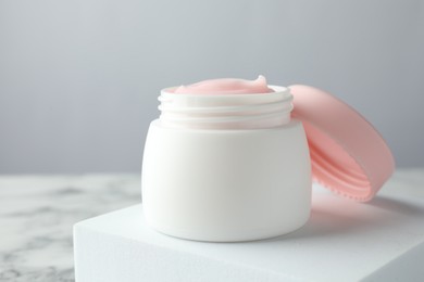Photo of Jar of moisturizing body cream on white marble table, closeup