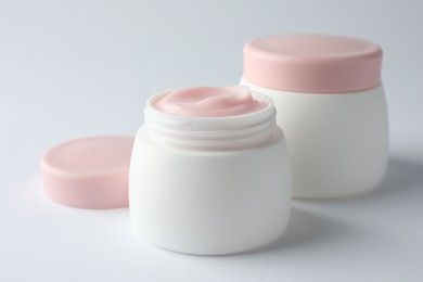 Photo of Jars of moisturizing body cream on white background, closeup