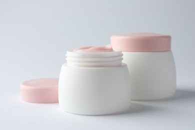 Photo of Jars of moisturizing body cream on white background, closeup