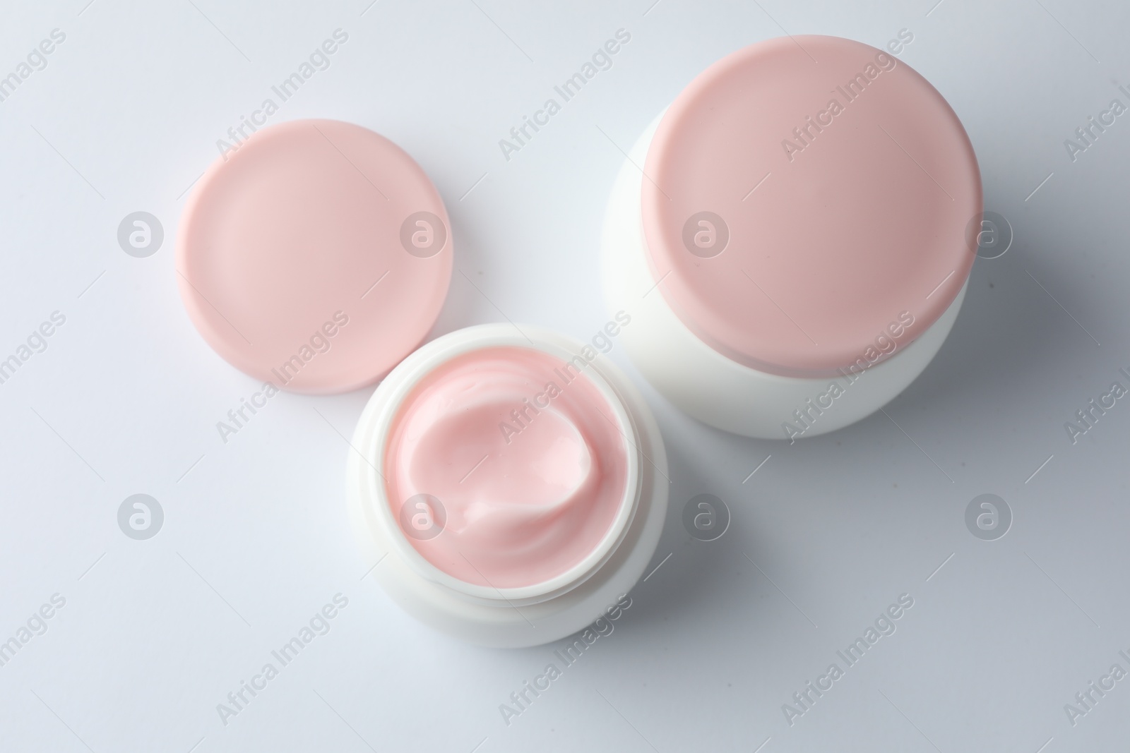 Jars of moisturizing body cream on white background, flat lay Photo of Jars of moisturizing body cream on white background, flat lay
