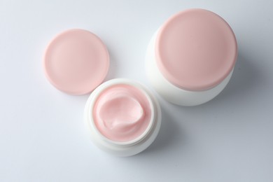 Photo of Jars of moisturizing body cream on white background, flat lay