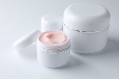 Photo of Jars of moisturizing body cream on white background, closeup