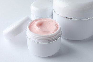 Photo of Jars of moisturizing body cream on white background, closeup
