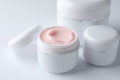Photo of Jars of moisturizing body cream on white background, closeup