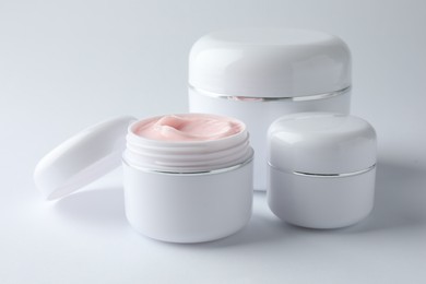 Photo of Jars of moisturizing body cream on white background, closeup