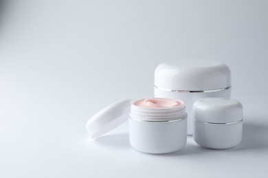 Photo of Jars of moisturizing body cream on white background