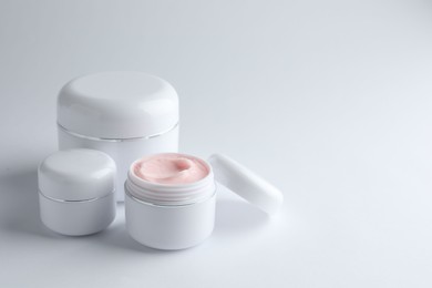 Photo of Jars of moisturizing body cream on white background