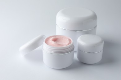 Photo of Jars of moisturizing body cream on white background, closeup