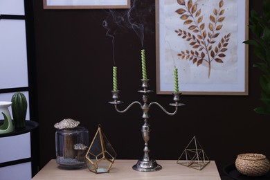 Photo of Elegant candlestick with candles and decor on table near brown wall