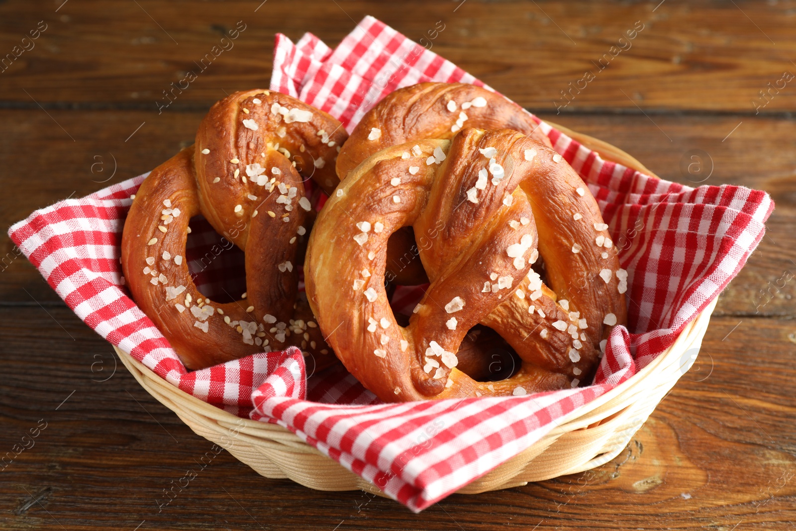 Tasty pretzels with salt in wicker basket on wooden table, closeup Photo of Tasty pretzels with salt in wicker basket on wooden table, closeup