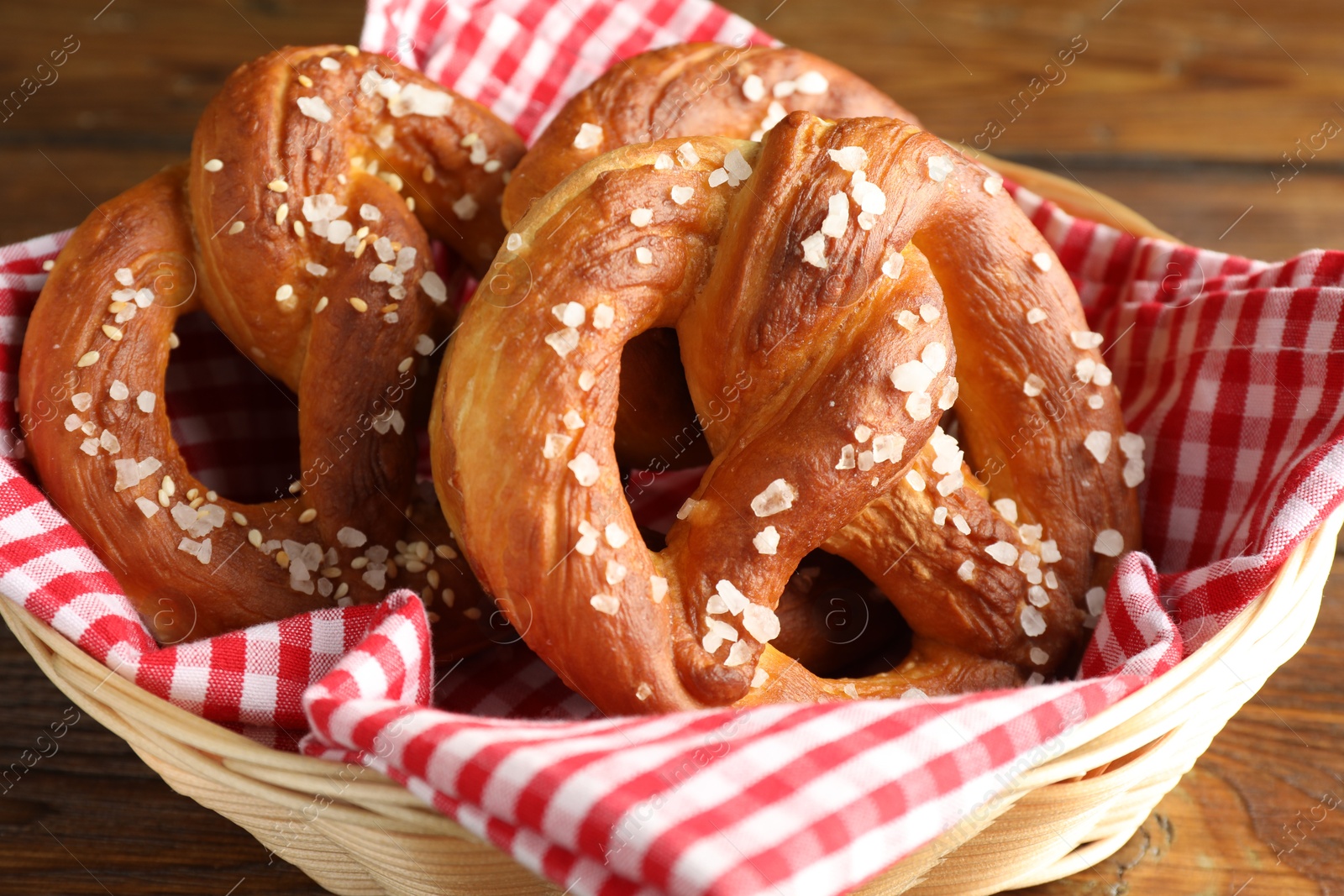 Tasty pretzels with salt in wicker basket on wooden table, closeup Photo of Tasty pretzels with salt in wicker basket on wooden table, closeup