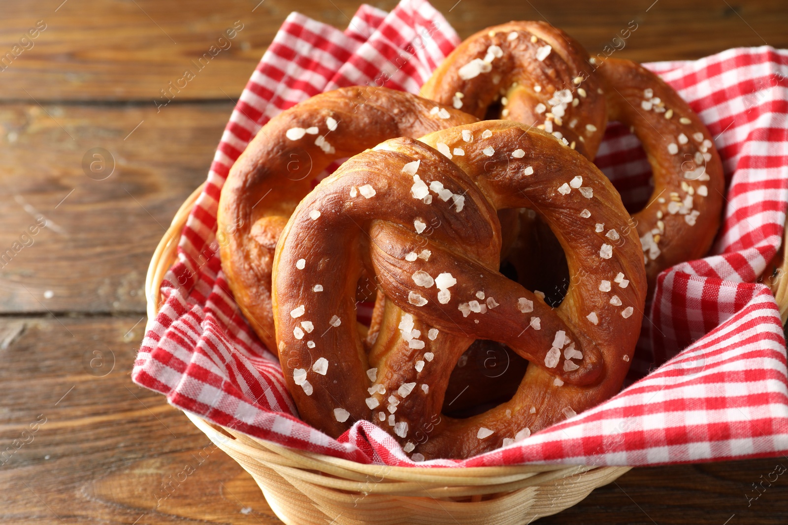 Tasty pretzels with salt in wicker basket on wooden table, closeup Photo of Tasty pretzels with salt in wicker basket on wooden table, closeup