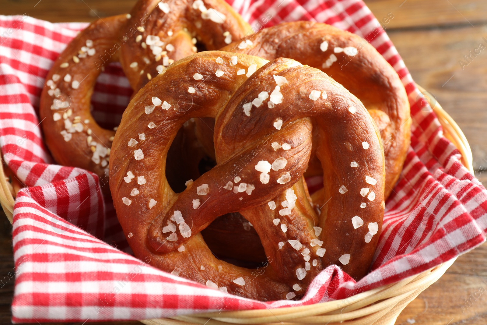 Tasty pretzels with salt in wicker basket on table, closeup Photo of Tasty pretzels with salt in wicker basket on table, closeup