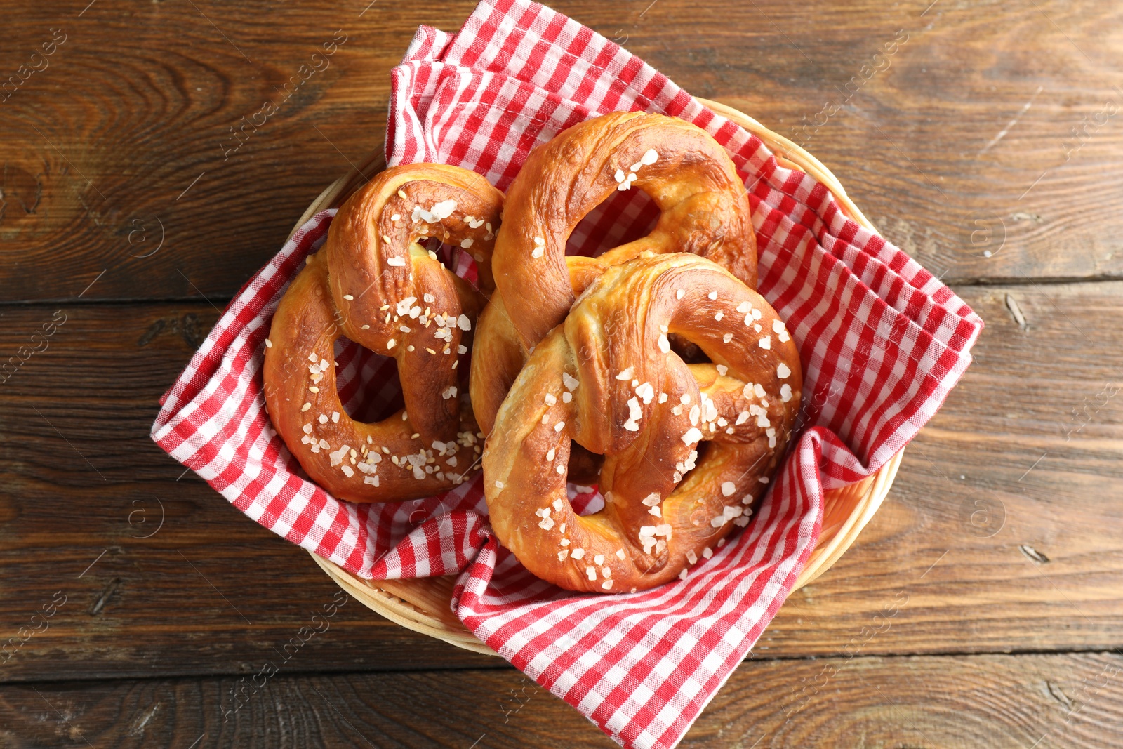Tasty pretzels with salt in wicker basket on wooden table, top view Photo of Tasty pretzels with salt in wicker basket on wooden table, top view