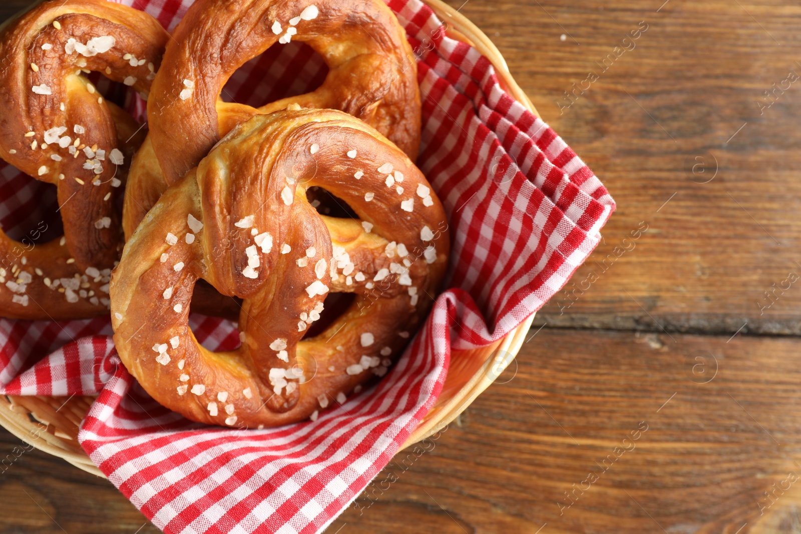 Tasty pretzels with salt in wicker basket on wooden table, top view. Space for text Photo of Tasty pretzels with salt in wicker basket on wooden table, top view. Space for text