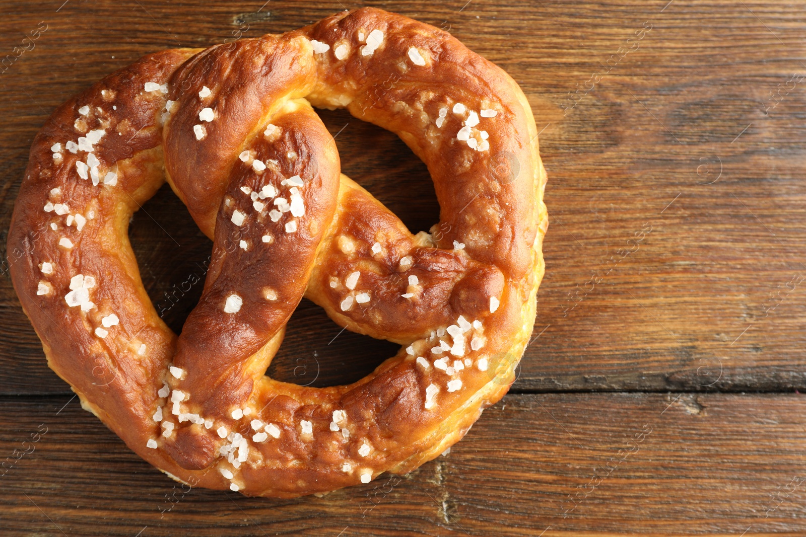 Tasty pretzel with salt on wooden table, top view. Space for text Photo of Tasty pretzel with salt on wooden table, top view. Space for text
