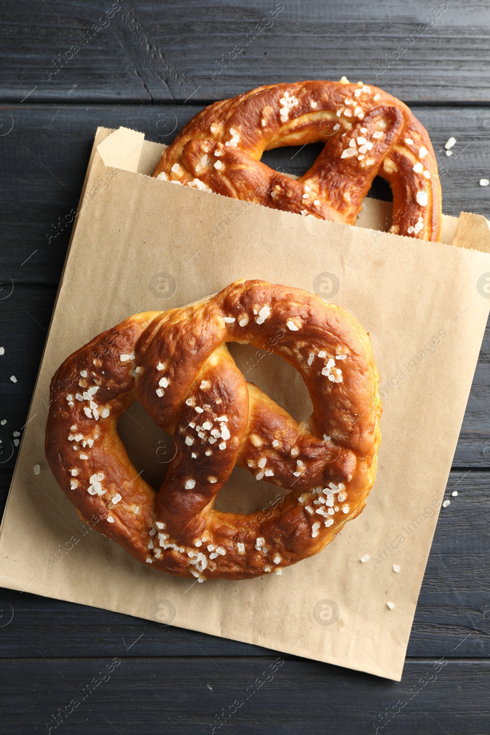 Tasty pretzels with salt on dark wooden table, top view Photo of Tasty pretzels with salt on dark wooden table, top view