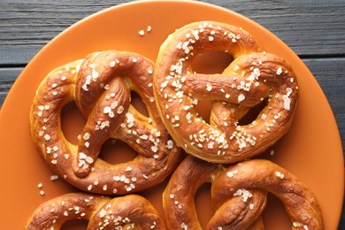 Photo of Tasty pretzels with salt on dark wooden table, top view