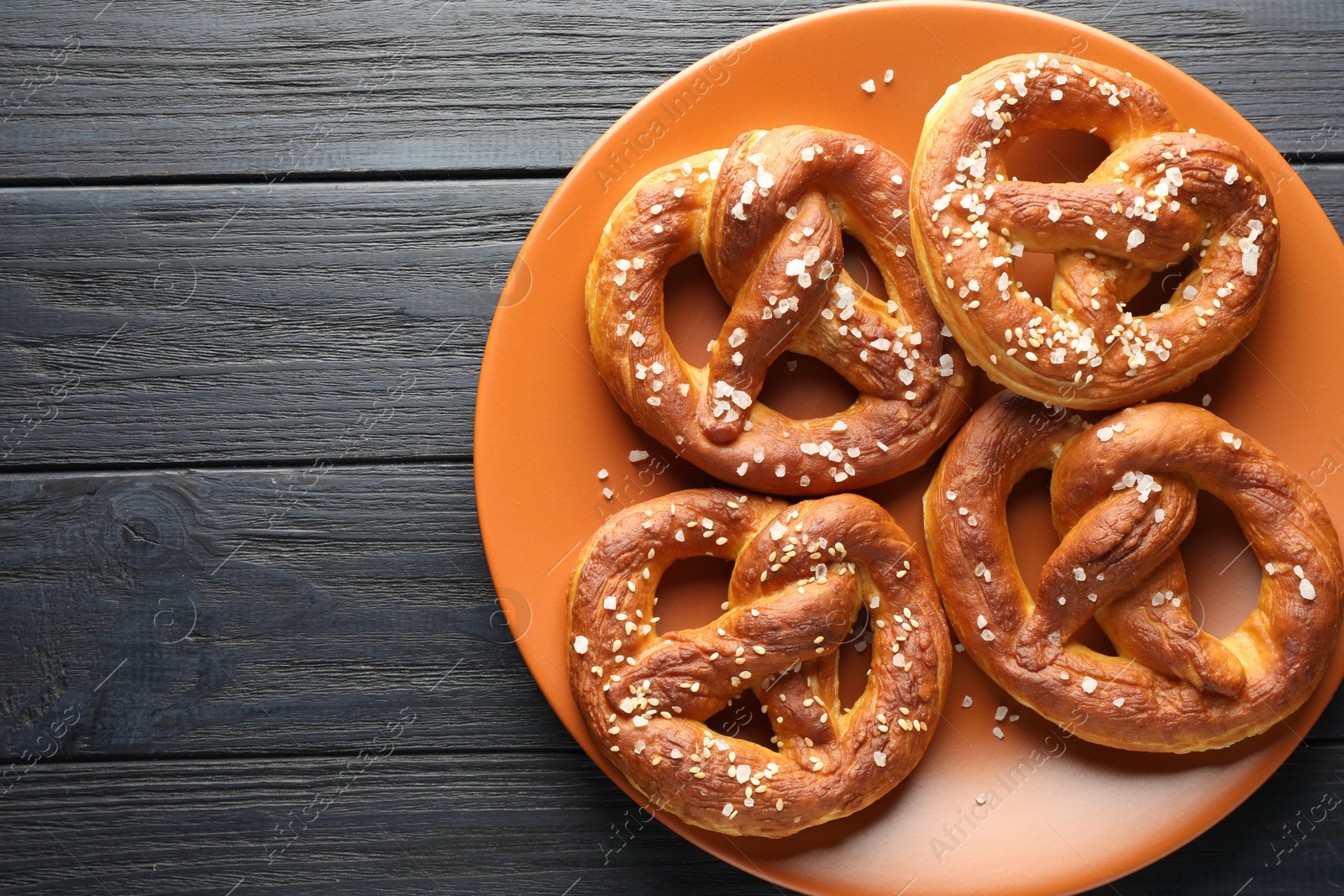 Tasty pretzels with salt on dark wooden table, top view. Space for text Photo of Tasty pretzels with salt on dark wooden table, top view. Space for text