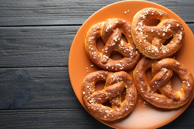 Photo of Tasty pretzels with salt on dark wooden table, top view. Space for text