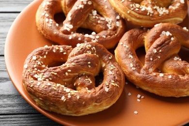Photo of Tasty pretzels with salt on dark wooden table, closeup