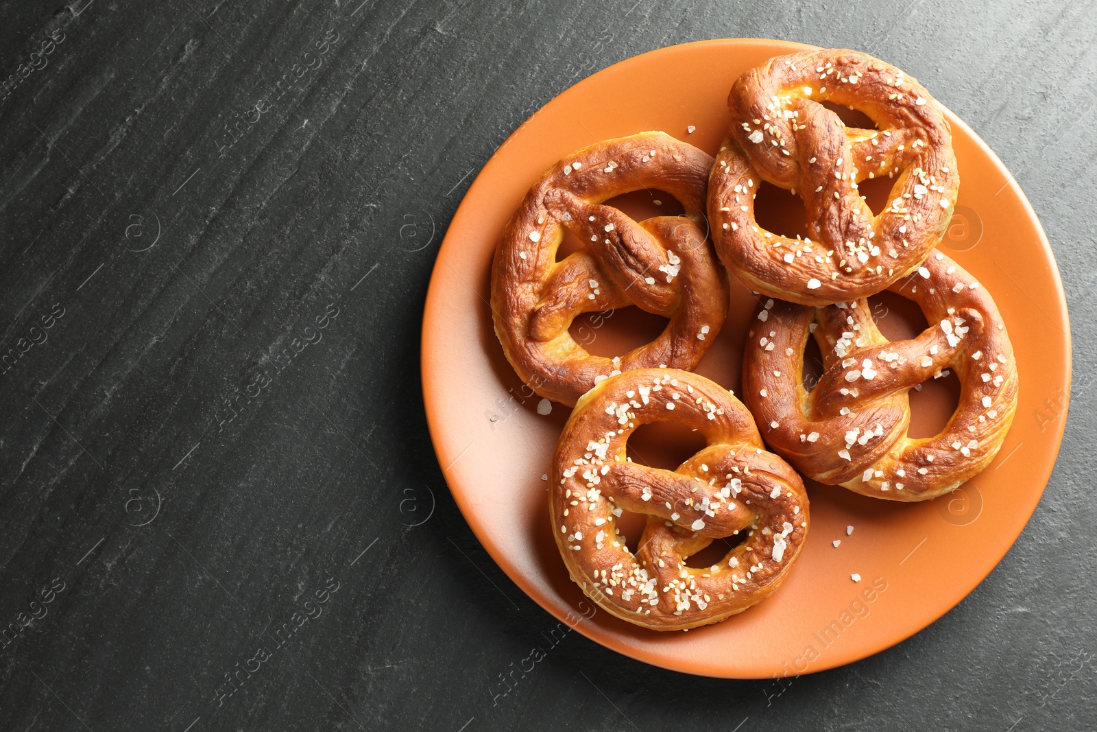 Tasty pretzels with salt on black table, top view. Space for text Photo of Tasty pretzels with salt on black table, top view. Space for text