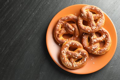 Photo of Tasty pretzels with salt on black table, top view. Space for text
