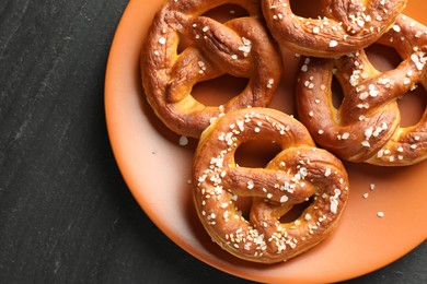 Photo of Tasty pretzels with salt on black table, top view. Space for text