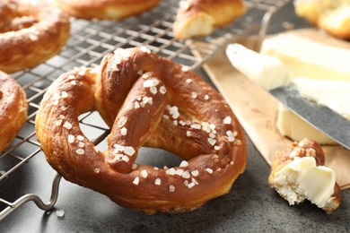 Photo of Tasty pretzels with salt and butter on grey table, closeup