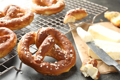 Photo of Tasty pretzels with salt and butter on grey table, closeup