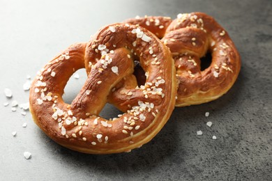 Photo of Tasty pretzels with salt on grey table, closeup