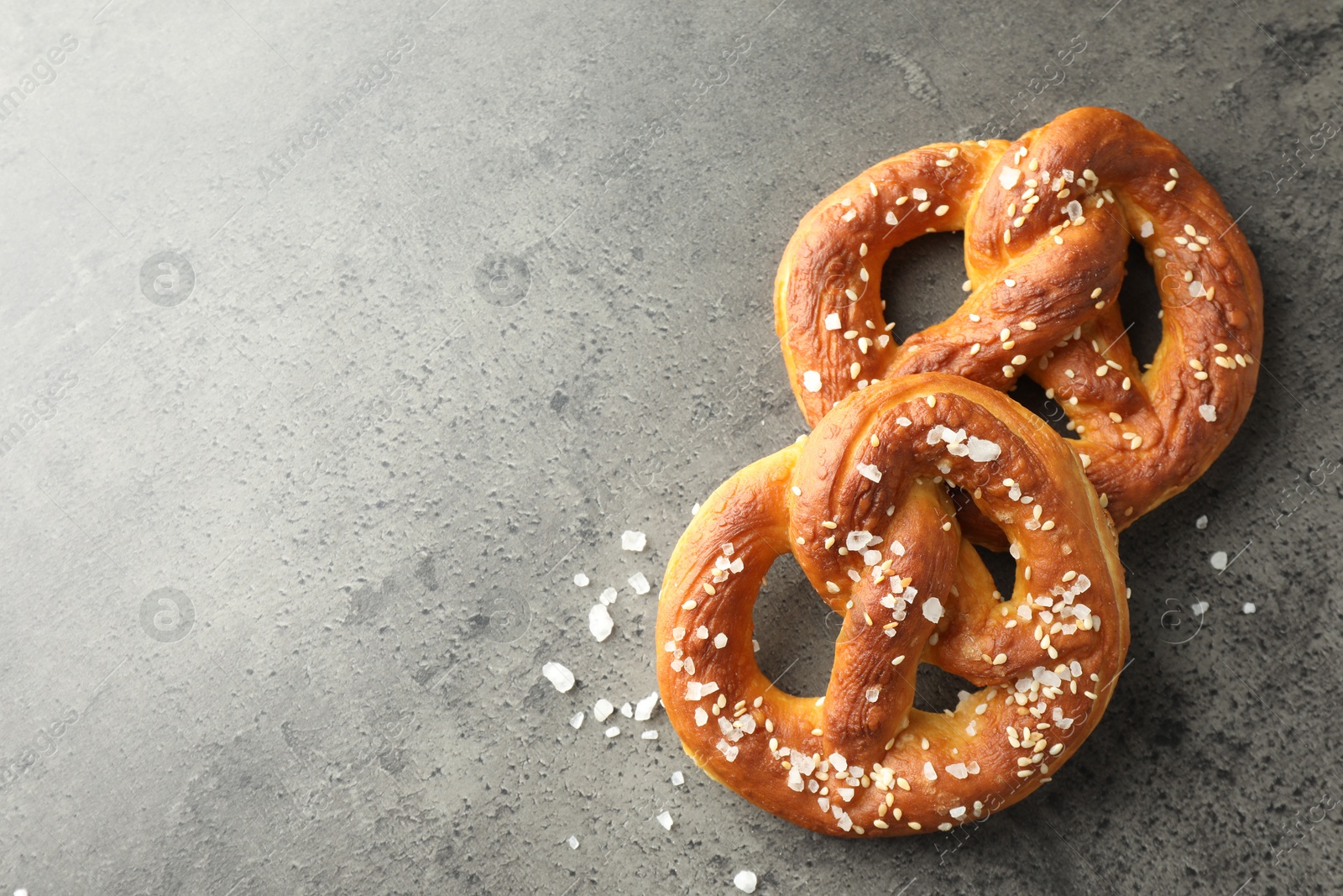 Tasty pretzels with salt on grey table, flat lay. Space for text Photo of Tasty pretzels with salt on grey table, flat lay. Space for text