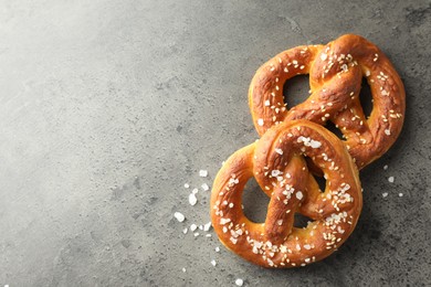 Photo of Tasty pretzels with salt on grey table, flat lay. Space for text