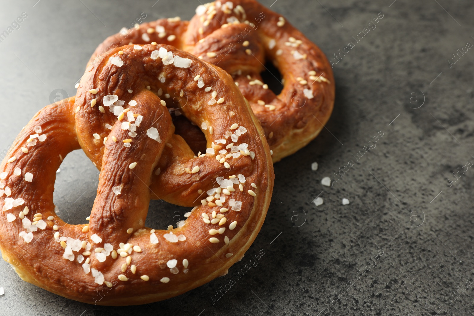 Tasty pretzels with salt on grey table, closeup. Space for text Photo of Tasty pretzels with salt on grey table, closeup. Space for text