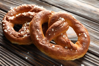 Photo of Tasty pretzels with salt on wooden table, closeup