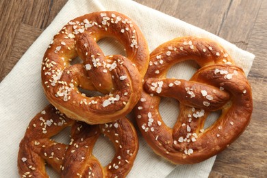 Photo of Tasty pretzels with salt on wooden table, flat lay