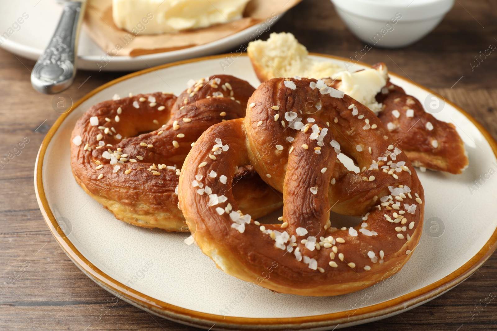 Tasty pretzels with salt and butter on wooden table, closeup Photo of Tasty pretzels with salt and butter on wooden table, closeup