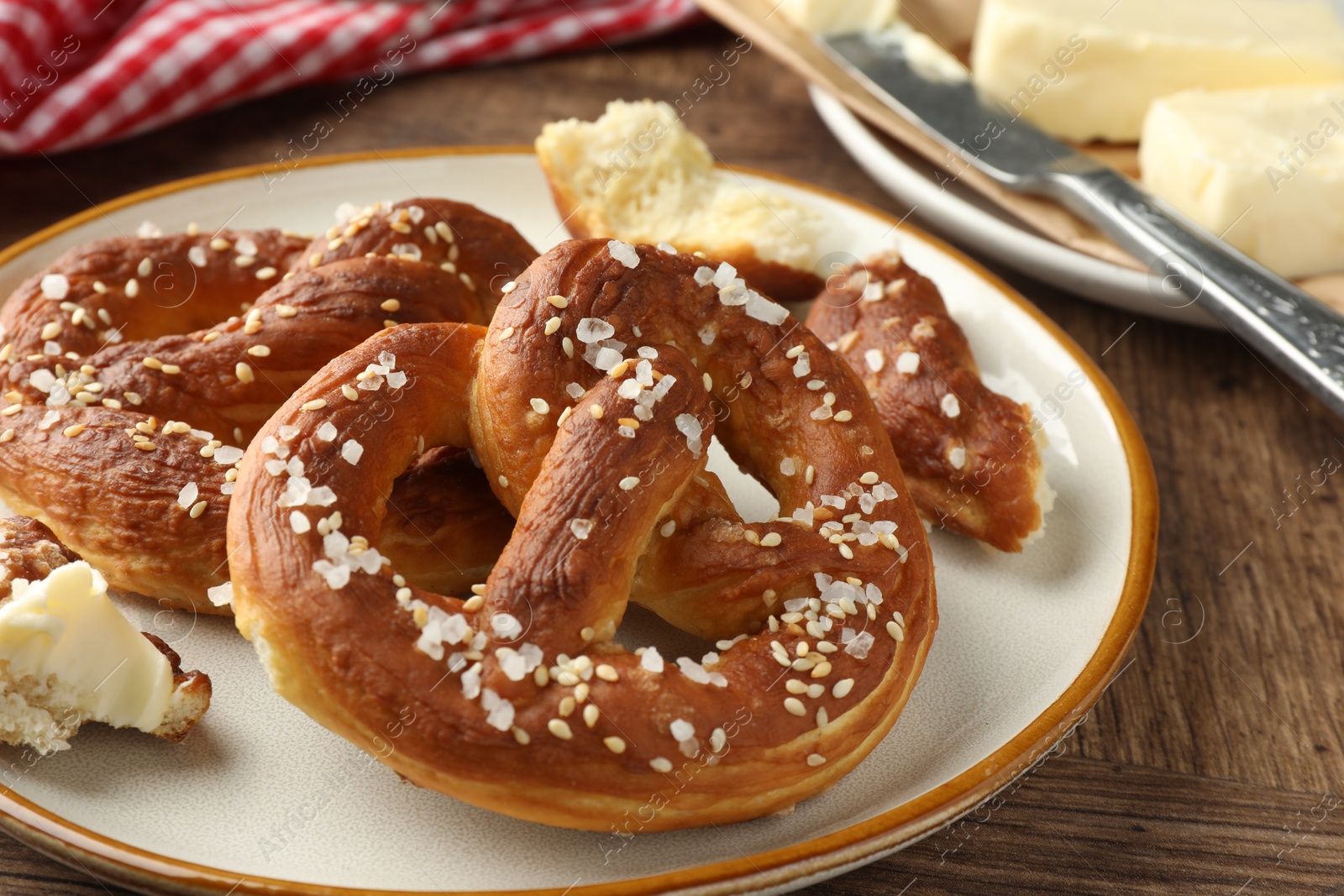 Tasty pretzels with salt and butter on wooden table, closeup Photo of Tasty pretzels with salt and butter on wooden table, closeup