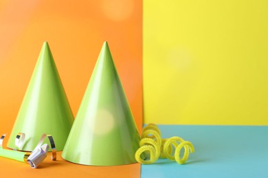 Photo of Beautiful party hats, streamers and blower on color background, space for text