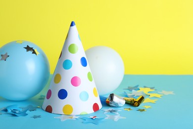 Photo of Beautiful party hat and other festive decor on color background, space for text