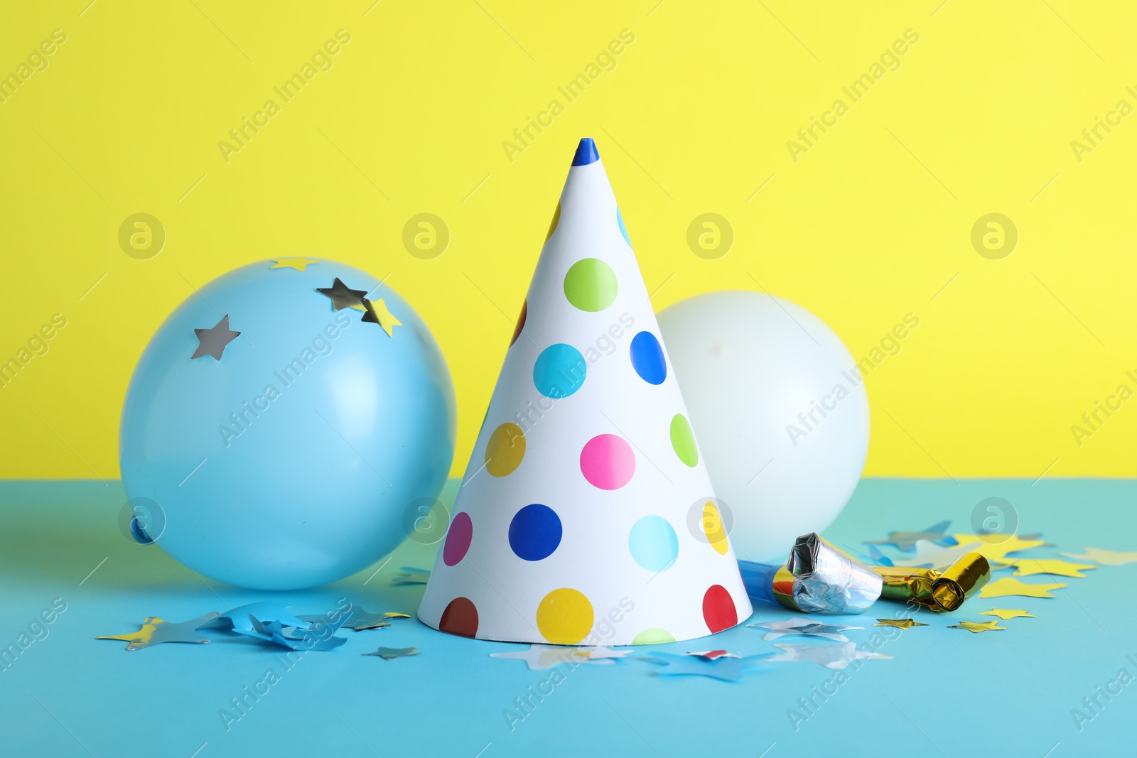 Beautiful party hat and other festive decor on color background Photo of Beautiful party hat and other festive decor on color background