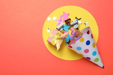 Photo of Beautiful party hat and other festive decor on red background, flat lay. Space for text