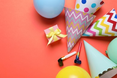 Photo of Beautiful party hats and other festive decor on red background, flat lay. Space for text