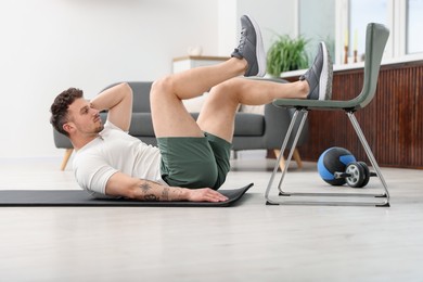 Photo of Handsome man exercising with chair at home