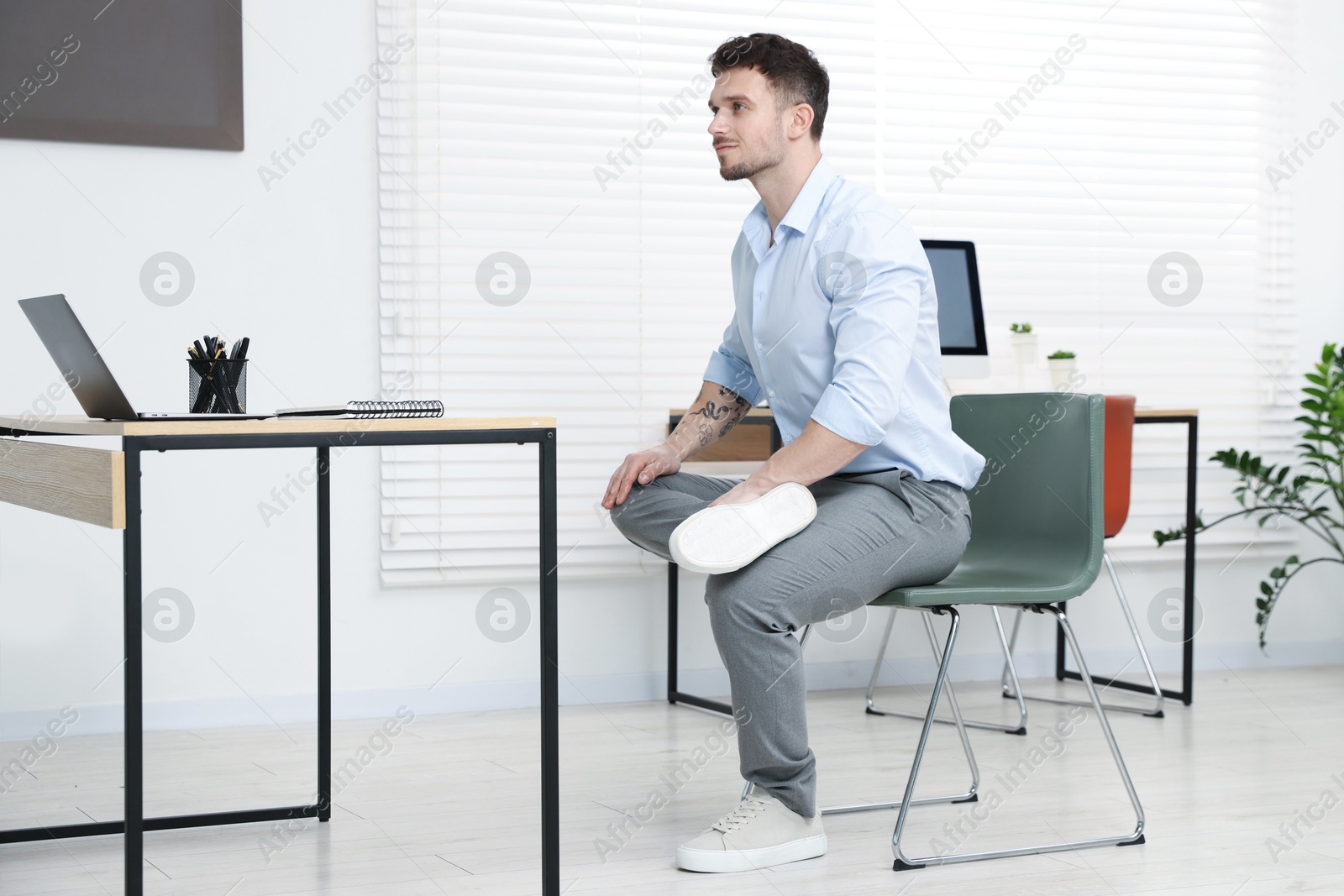 Handsome man exercising with chair in office Photo of Handsome man exercising with chair in office